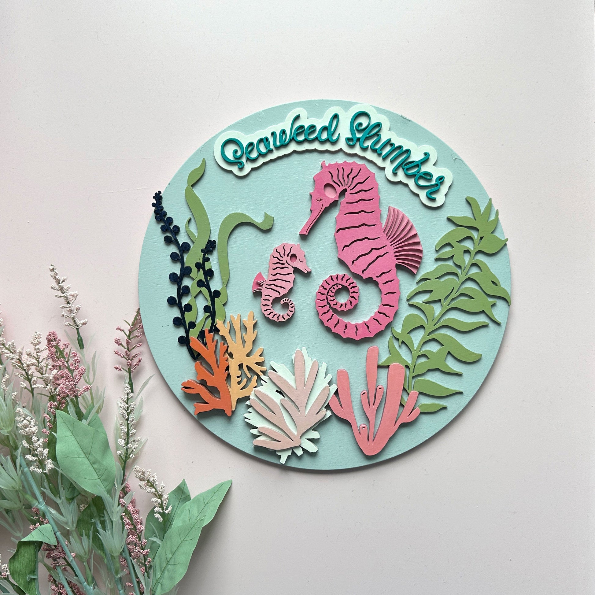 Decorative round cutout with seahorses and seaweed design on a light background