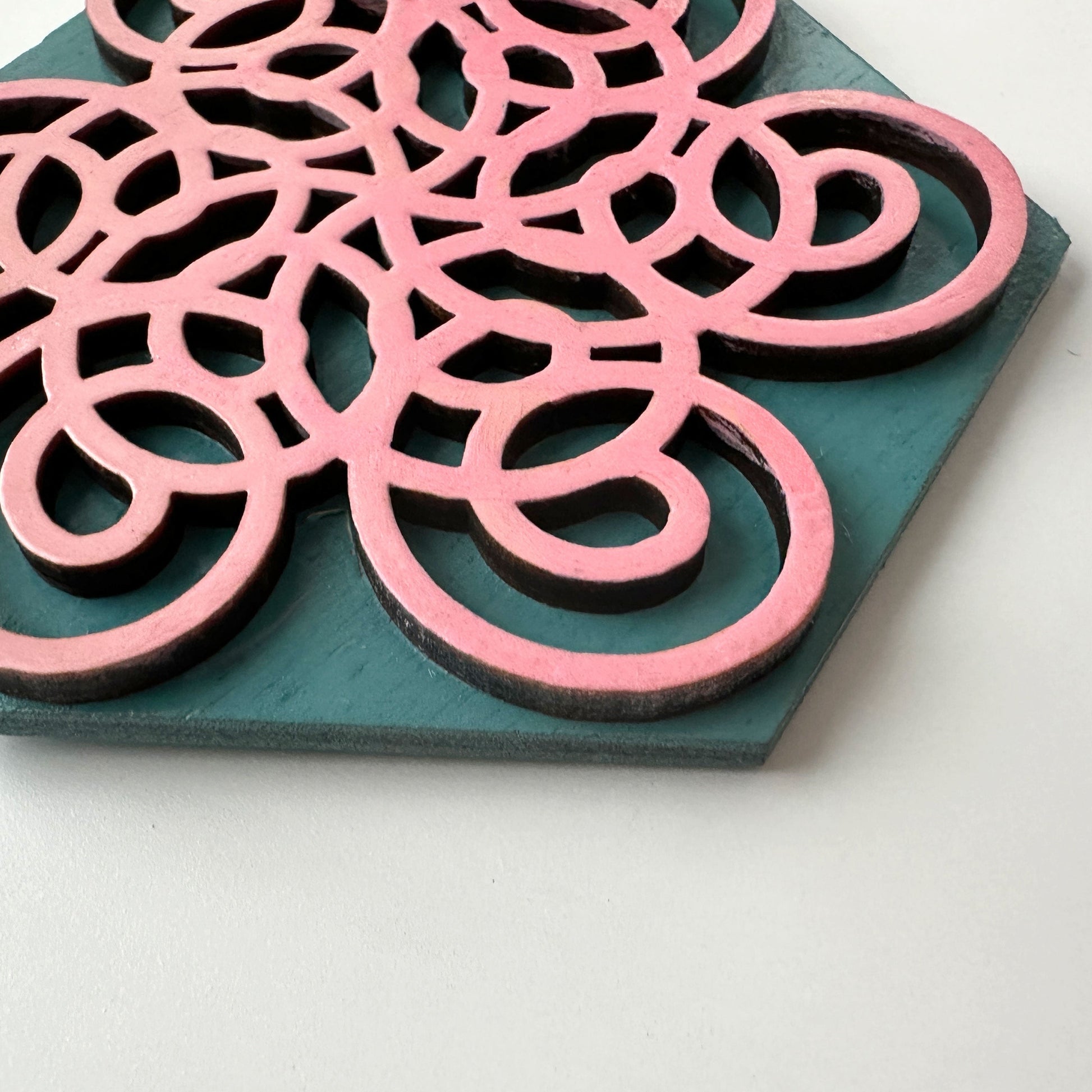 Decorative item with pink and black circular patterns on a teal base
