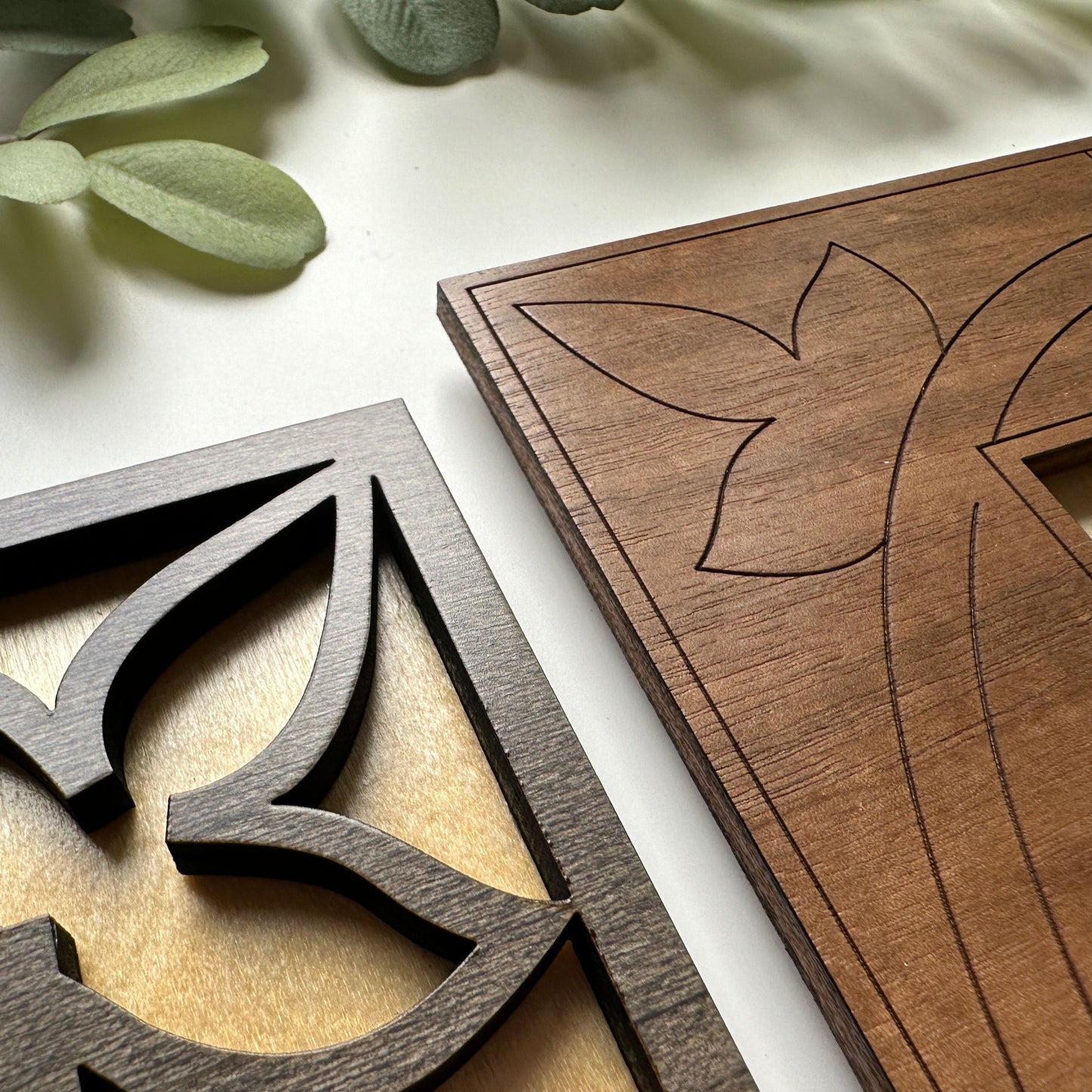 Close-up of two wooden decorative panels with intricate carvings on a light background.