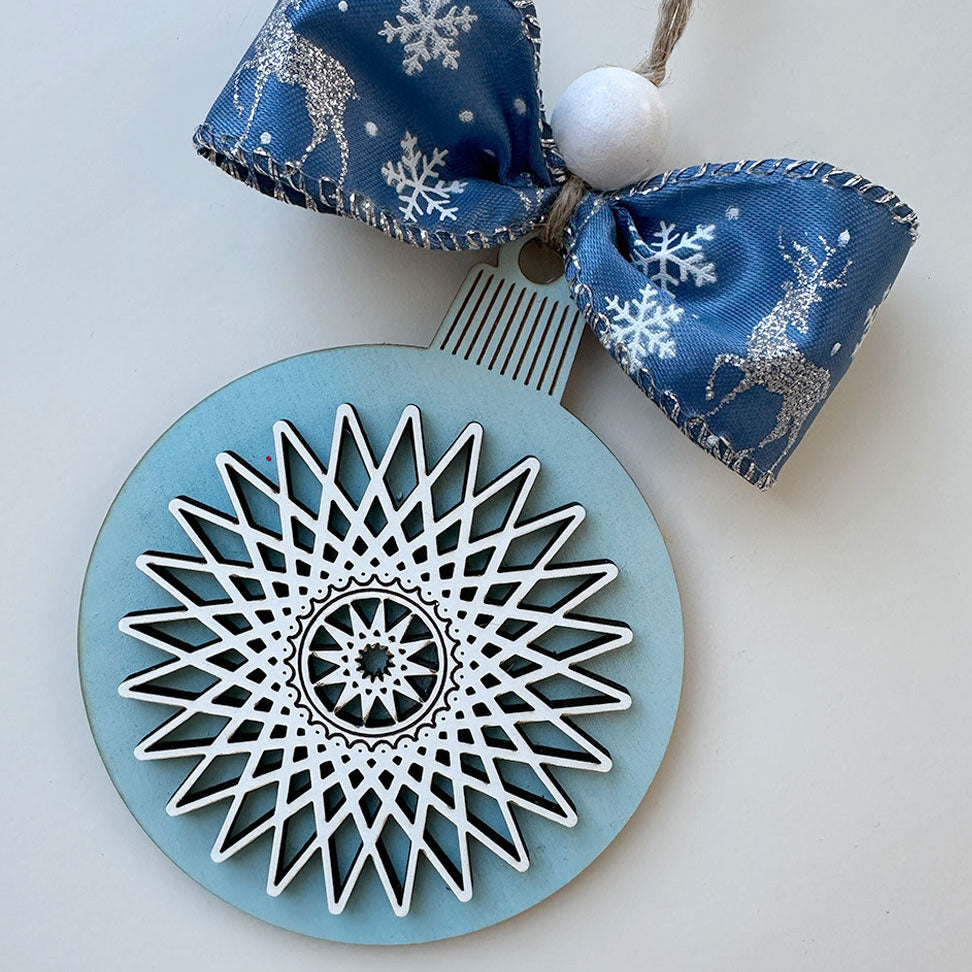 Decorative ornament with blue and white snowflake design on a light gray background