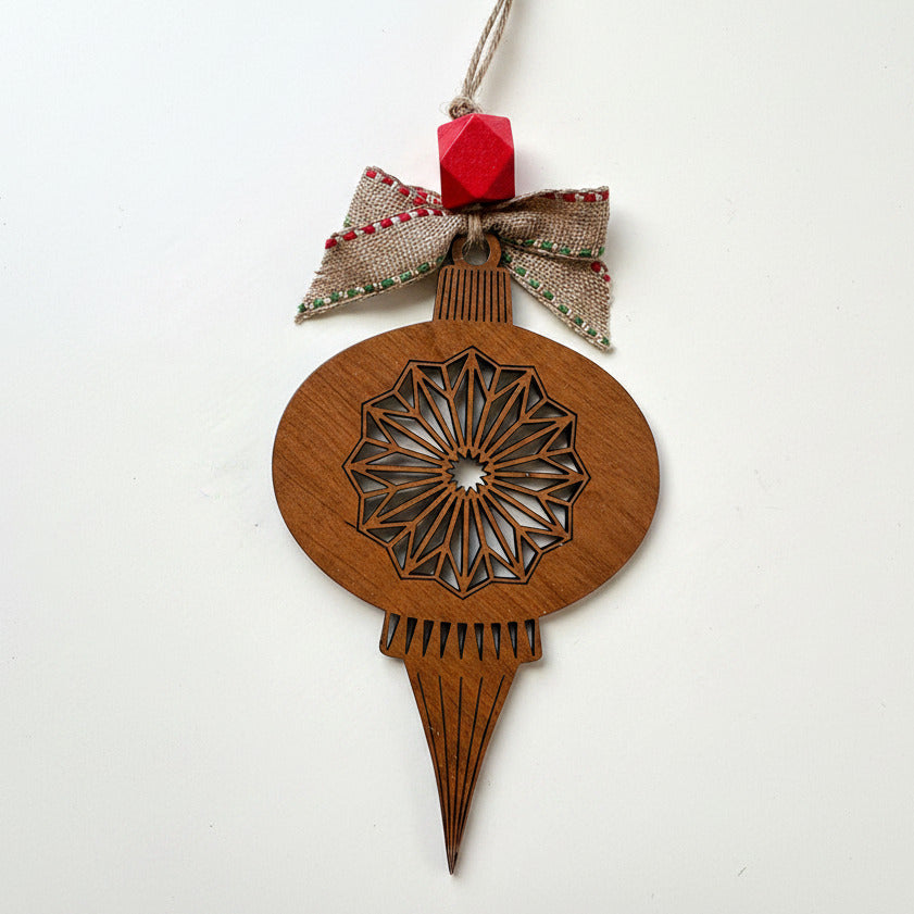 Wooden Christmas ornament with geometric design and red gem on a white background