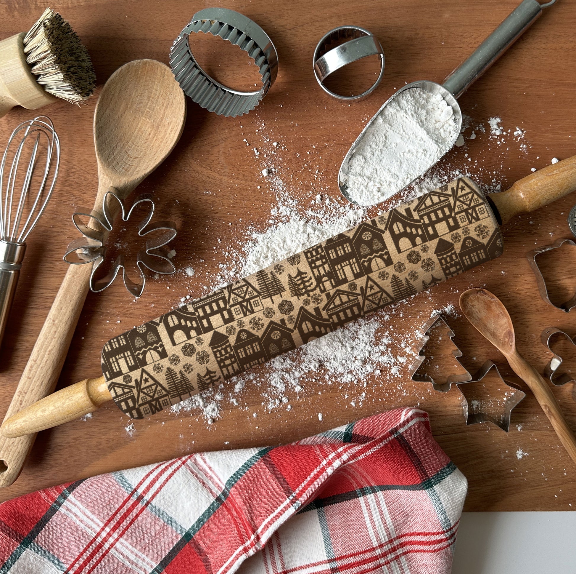 Baking tools including a rolling pin with embossed designs on a wooden surface.