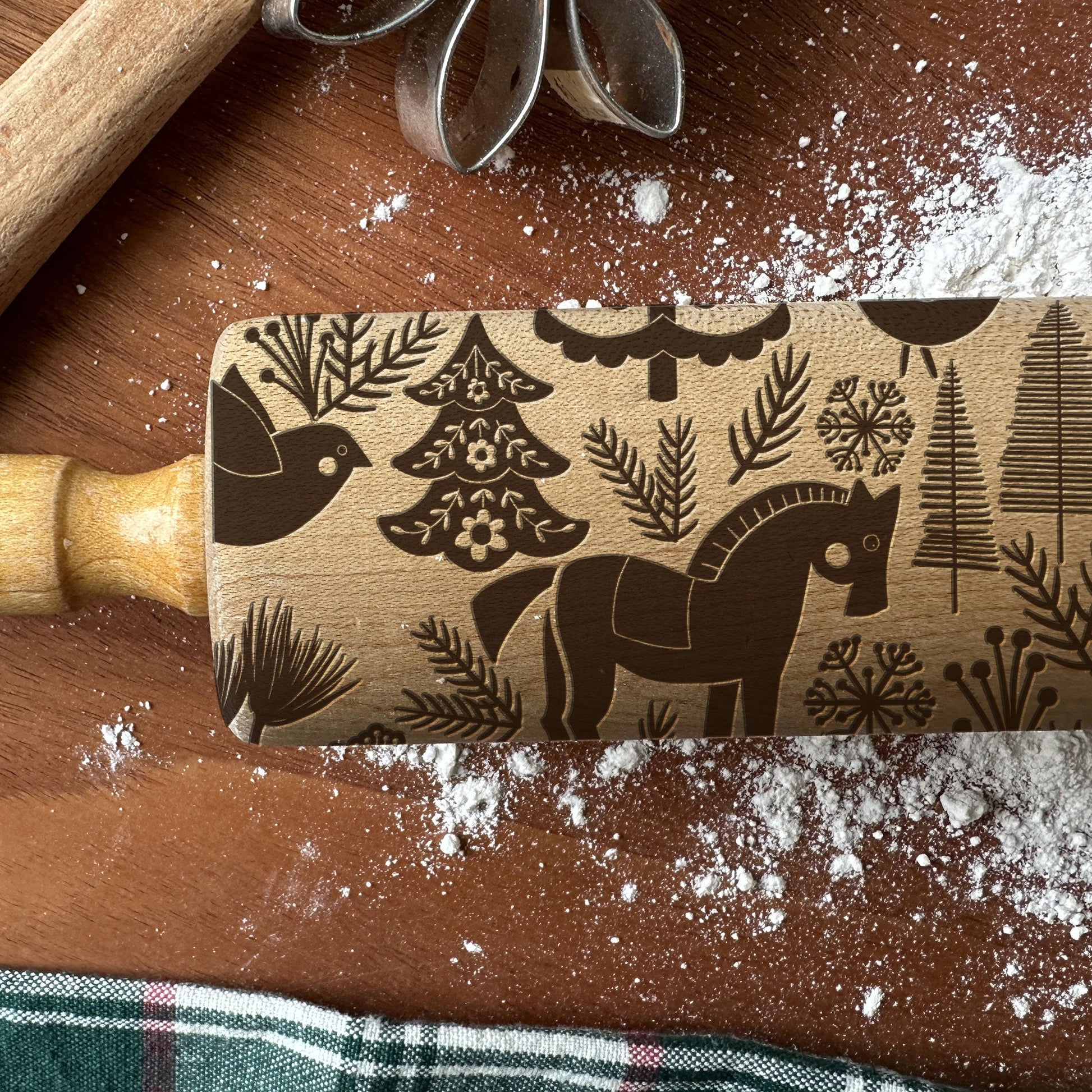Wooden rolling pin with embossed designs on a wooden surface with flour.